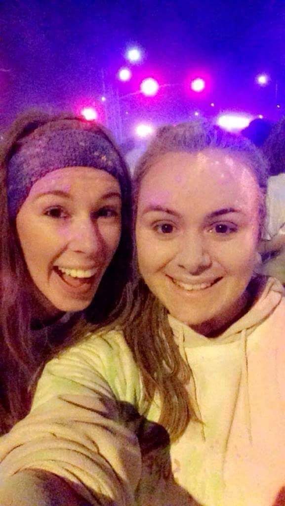 Jenna wearing blue headband smiling beside Lauren during a 5k night run.