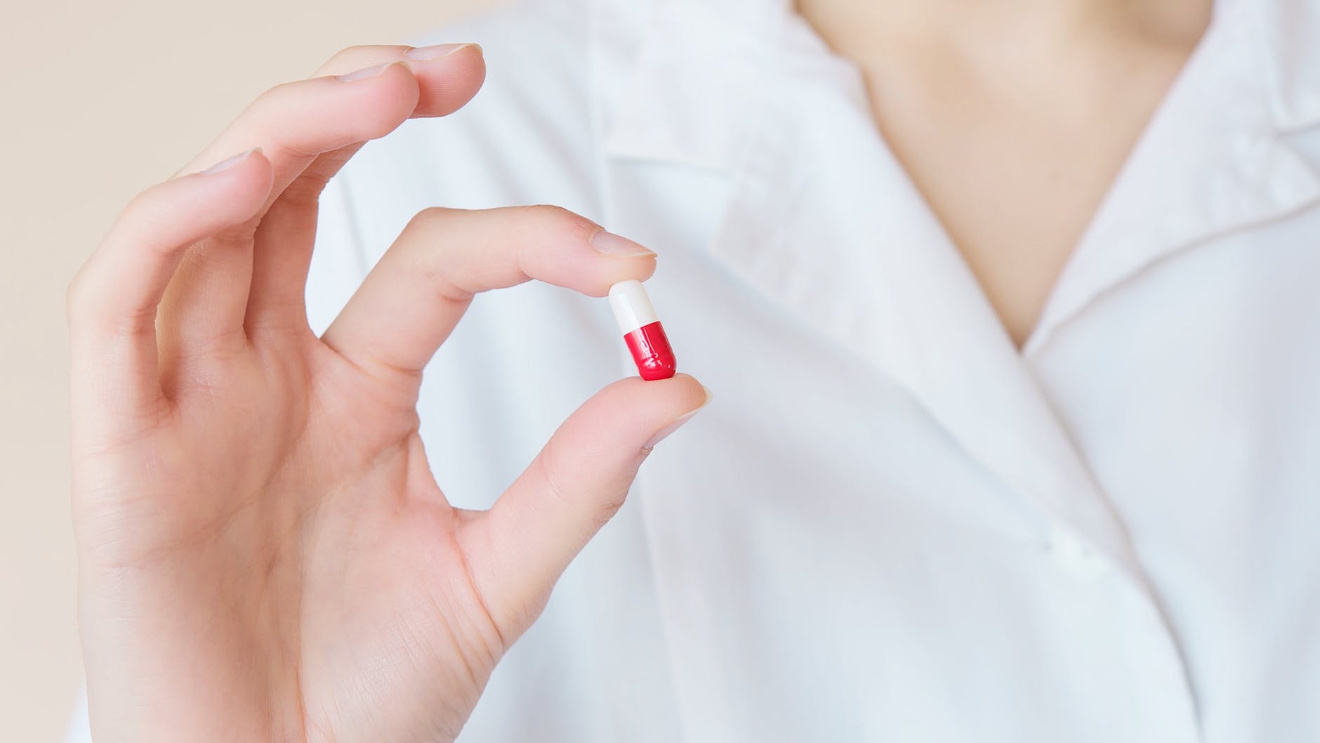 Woman in white shirt holding a red and white pill