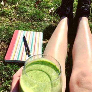 Me sitting in grass next to notebook and holding a smoothie