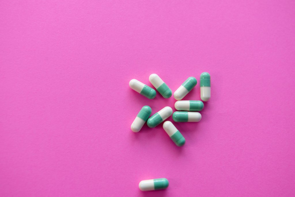 Pink and green pills laying against purple counter