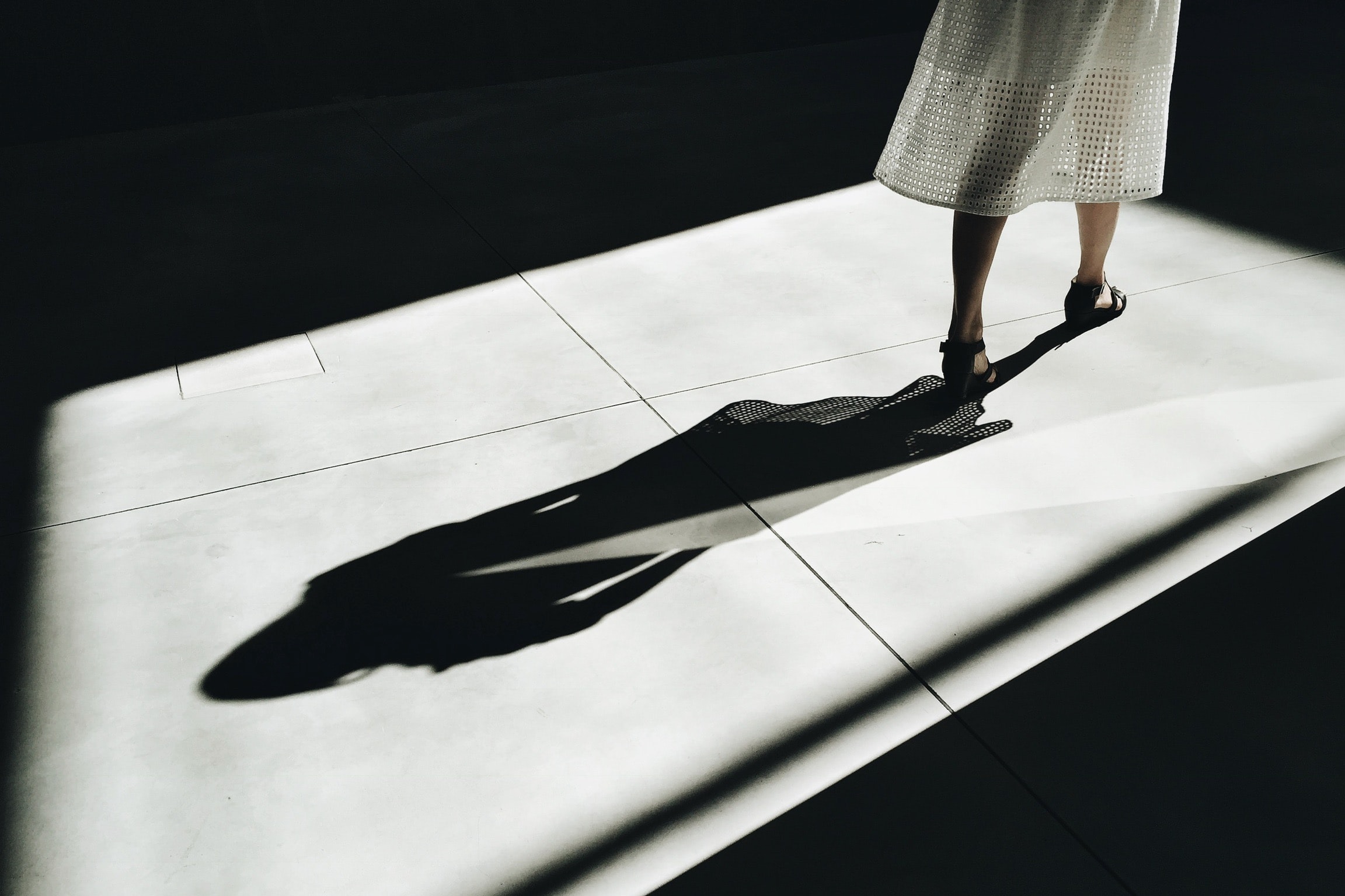 Image of woman's shadow as woman in flowing white dress walks out of the frame