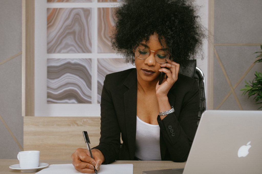 Woman self-advocating on the phone while taking notes