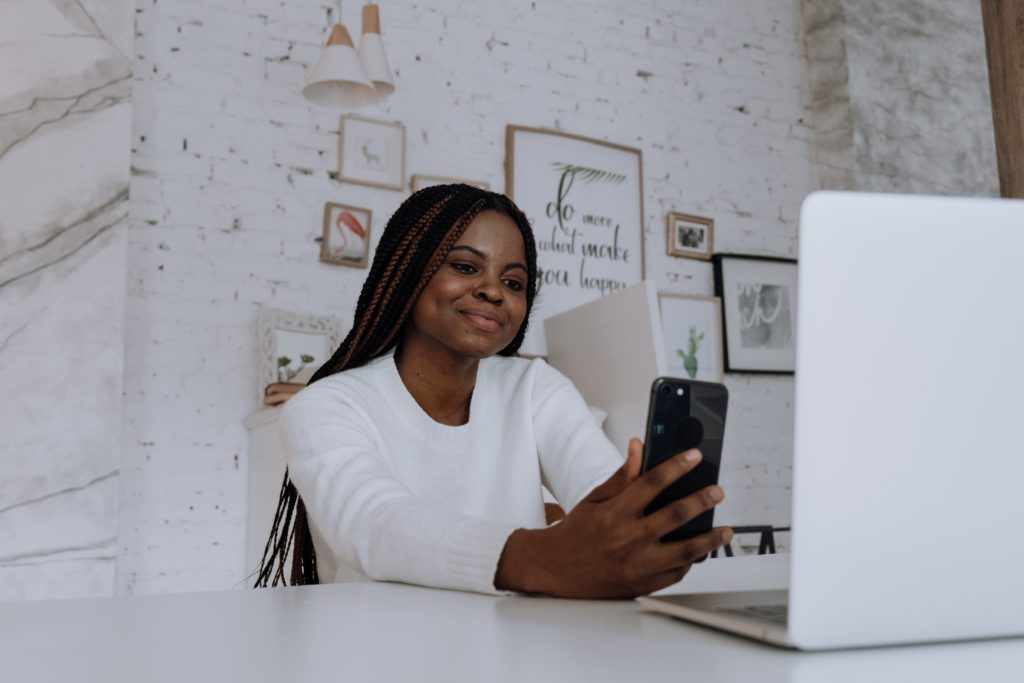 Woman sitting at desk smiling into phone as she Facetimes someone