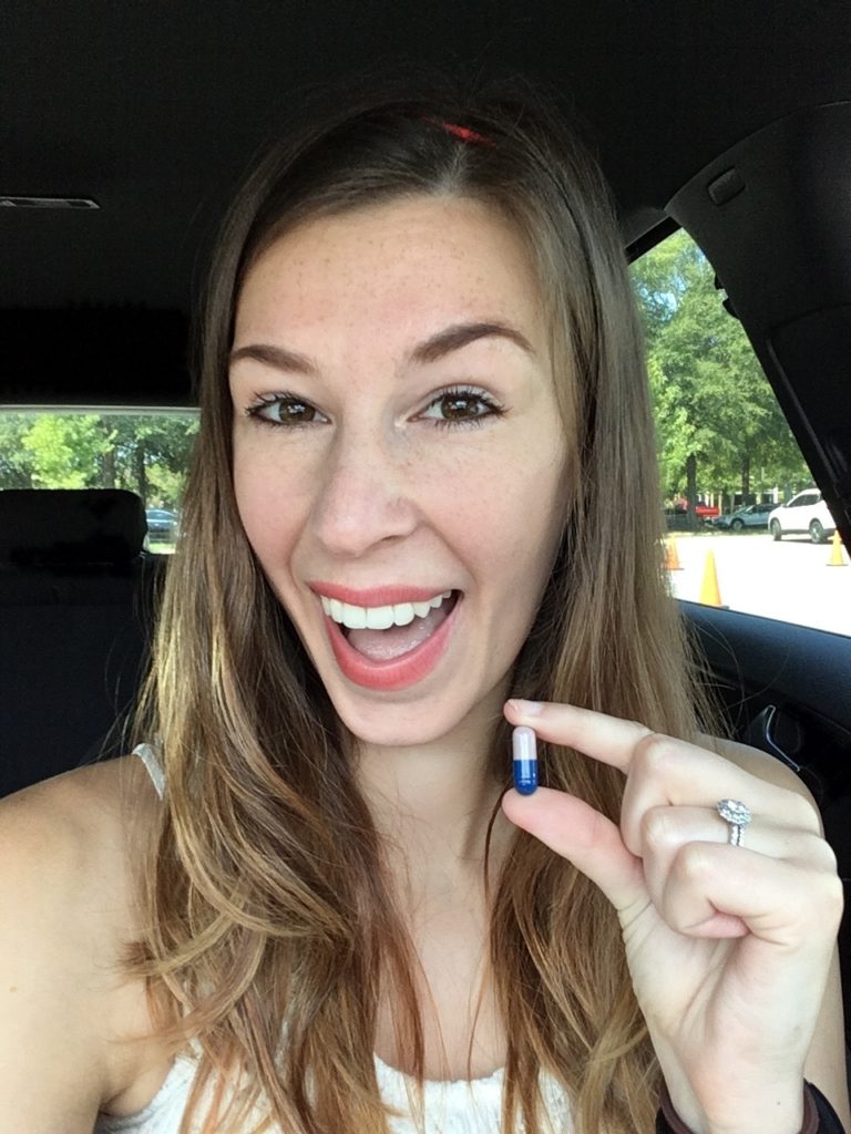 Jenna holding vancomycin pill in car and smiling