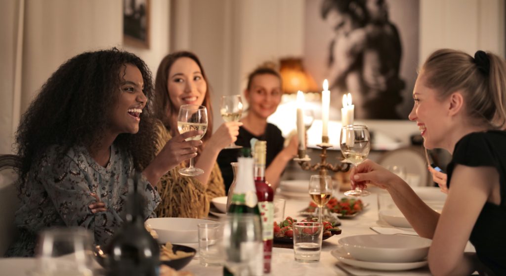 Group of women around dinner table talking and laughing