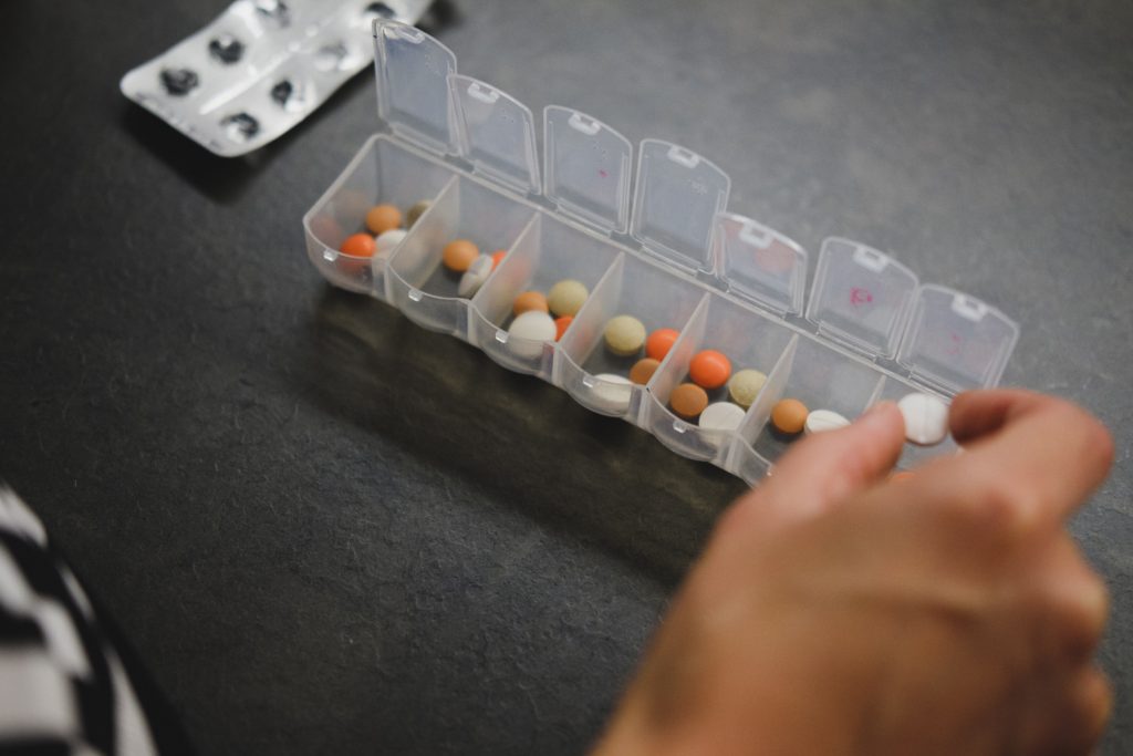 Woman sorting four kinds of pills into clear pill box.