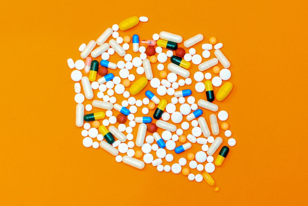 Pile of multi-colored pills on orange background