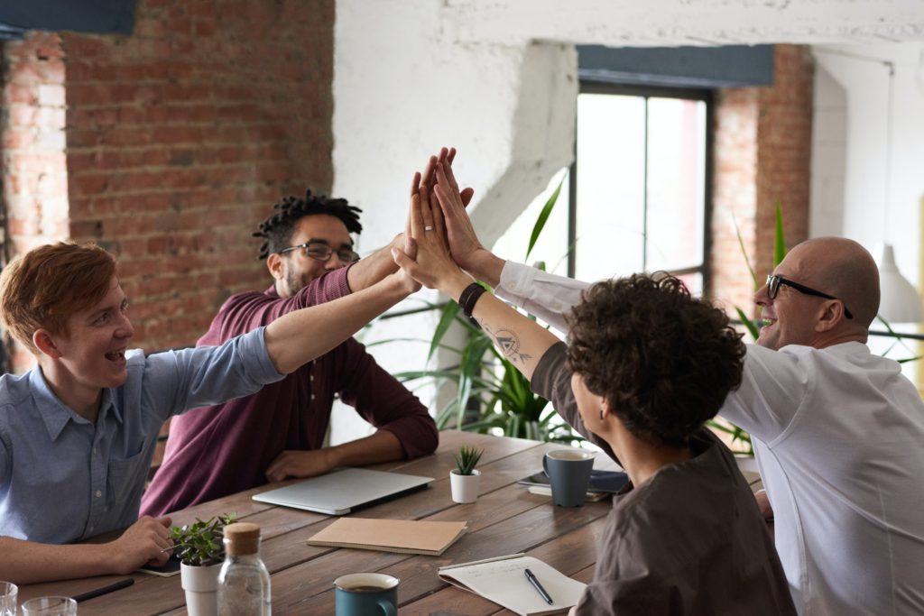 Team of patient advocates high-fiving at table