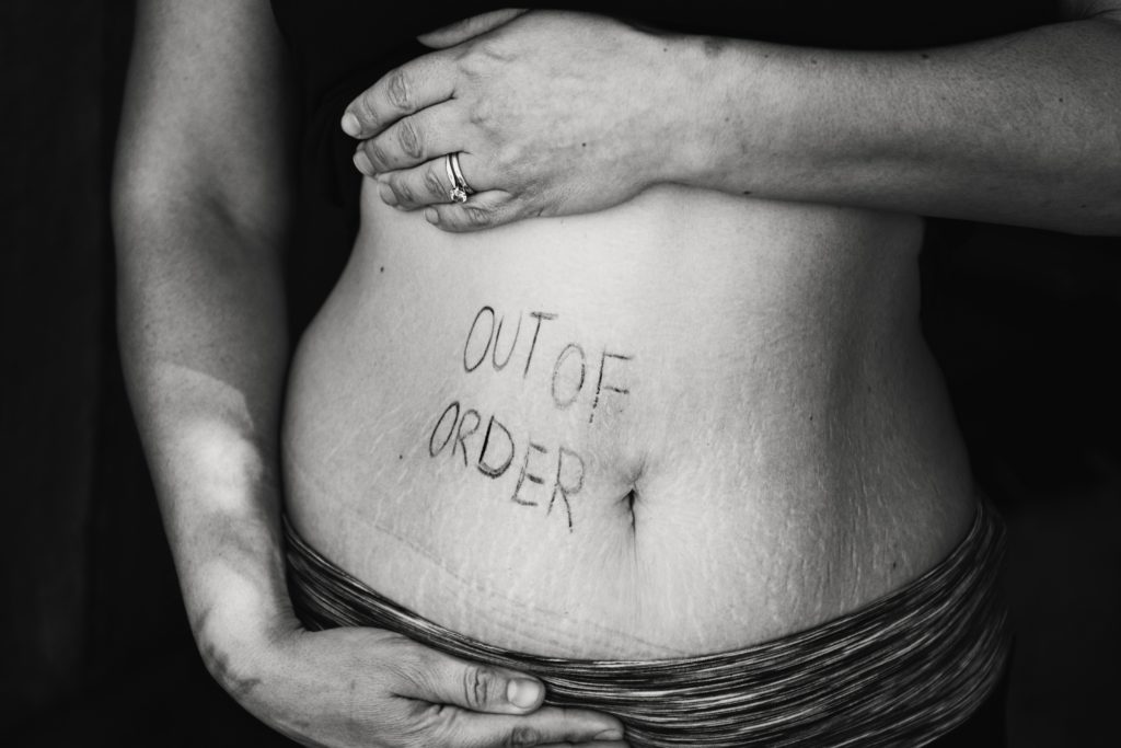 Woman in crop top with writing on her belly that reads, "Out of order"