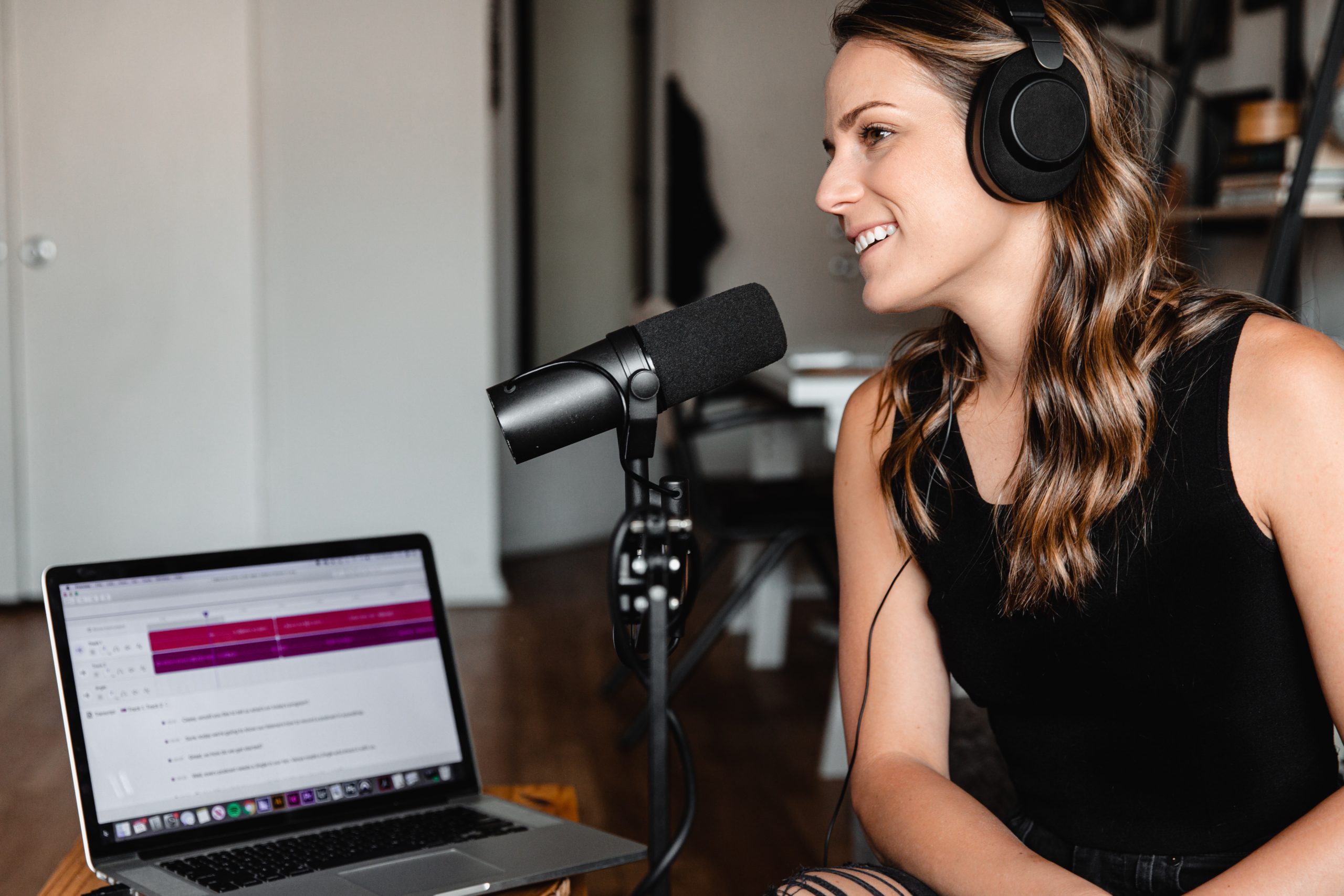 woman sitting next to laptop wearing headphones recording PSC podcast