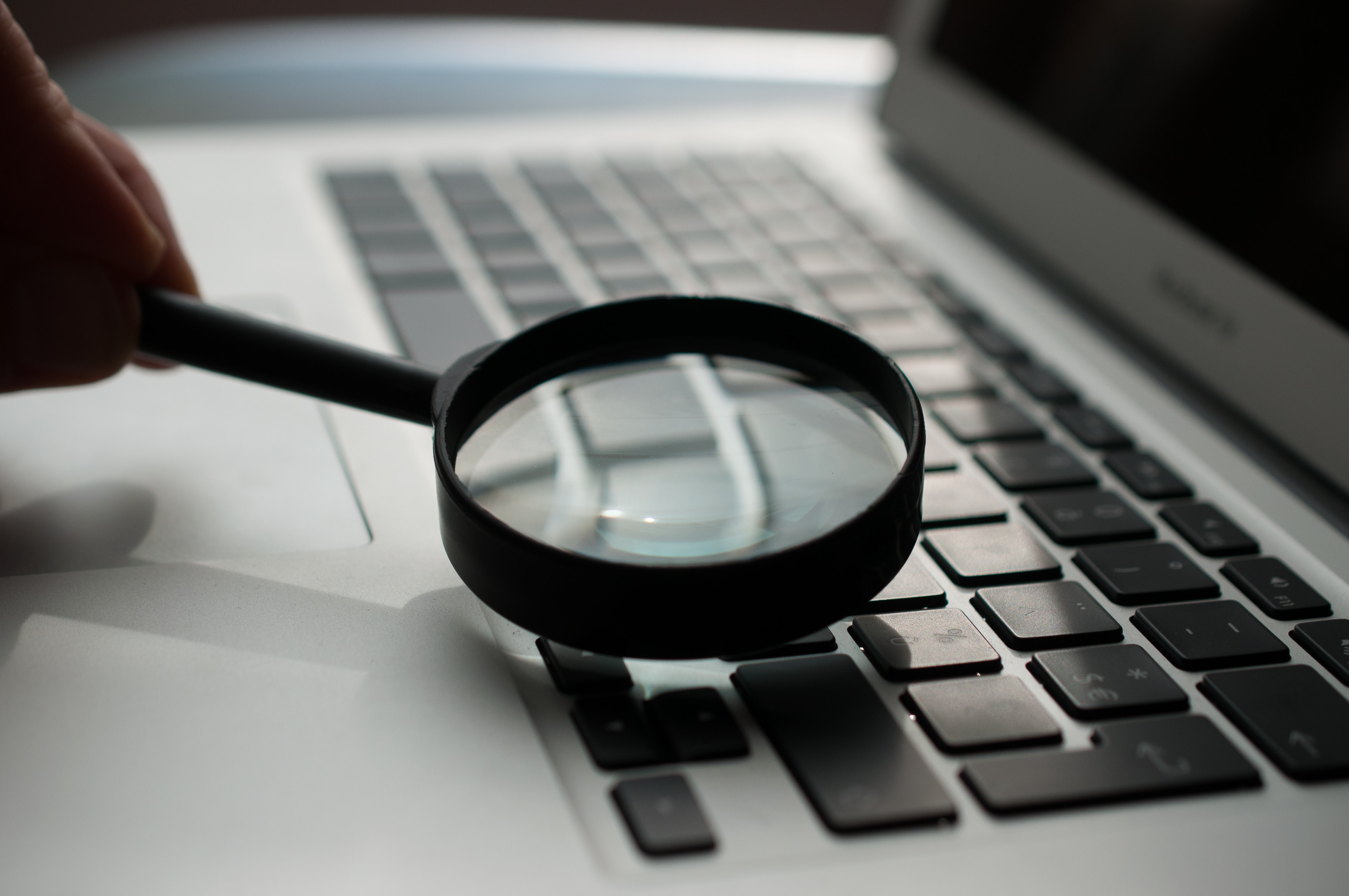 Magnifying glass on laptop keyboard to search for a topic