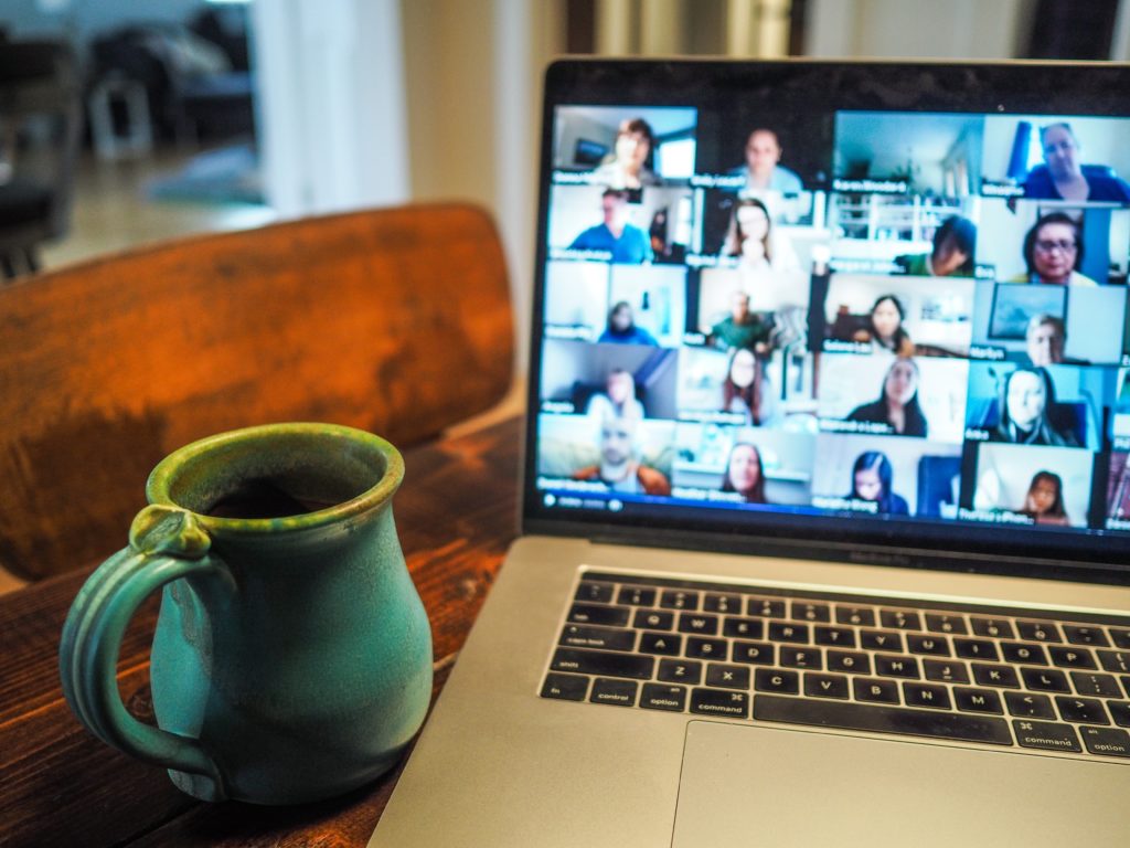 Blue coffee mug beside laptop with Zoom call