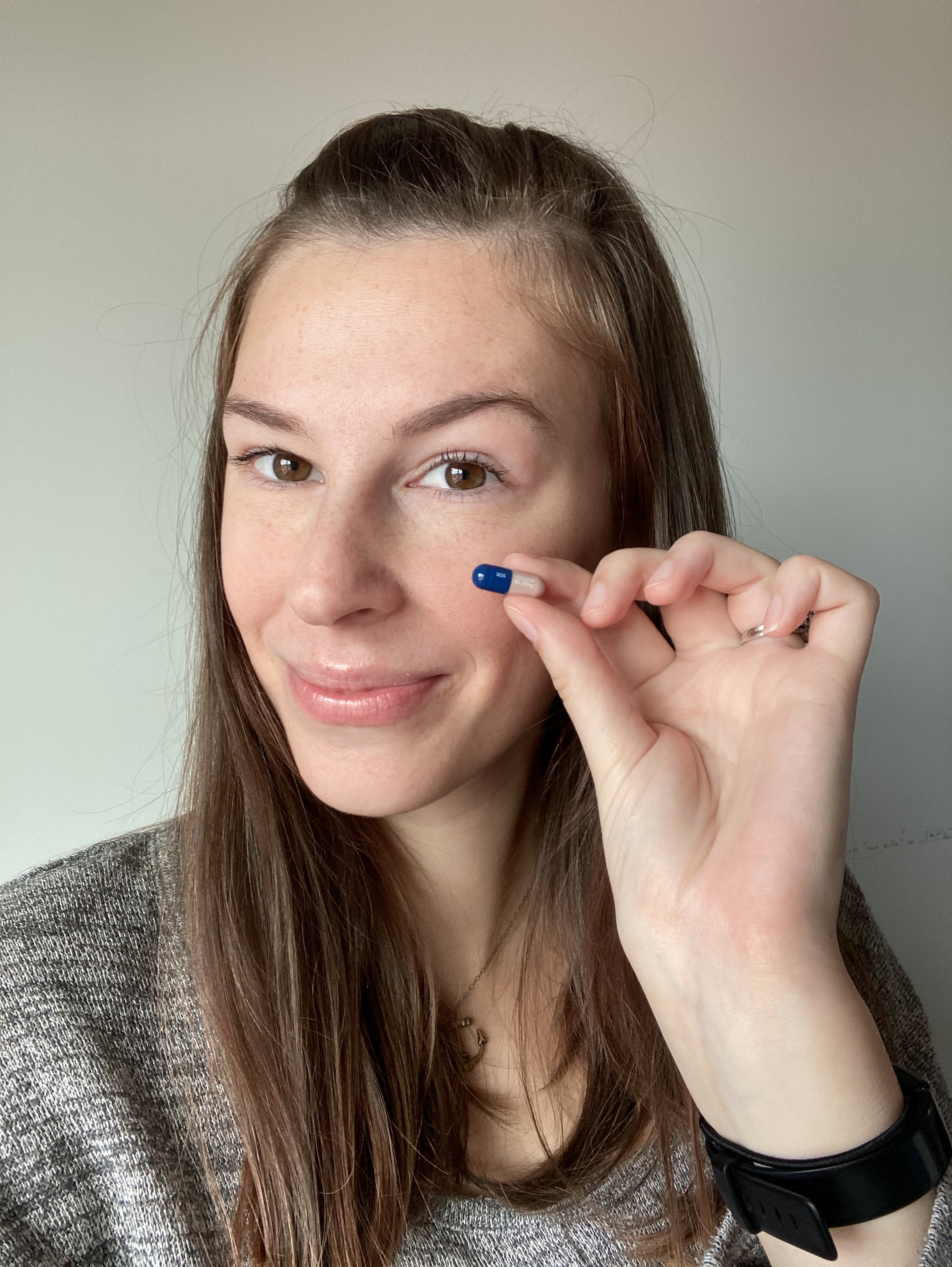 Jenna holding blue and pink vancomycin pill close to face