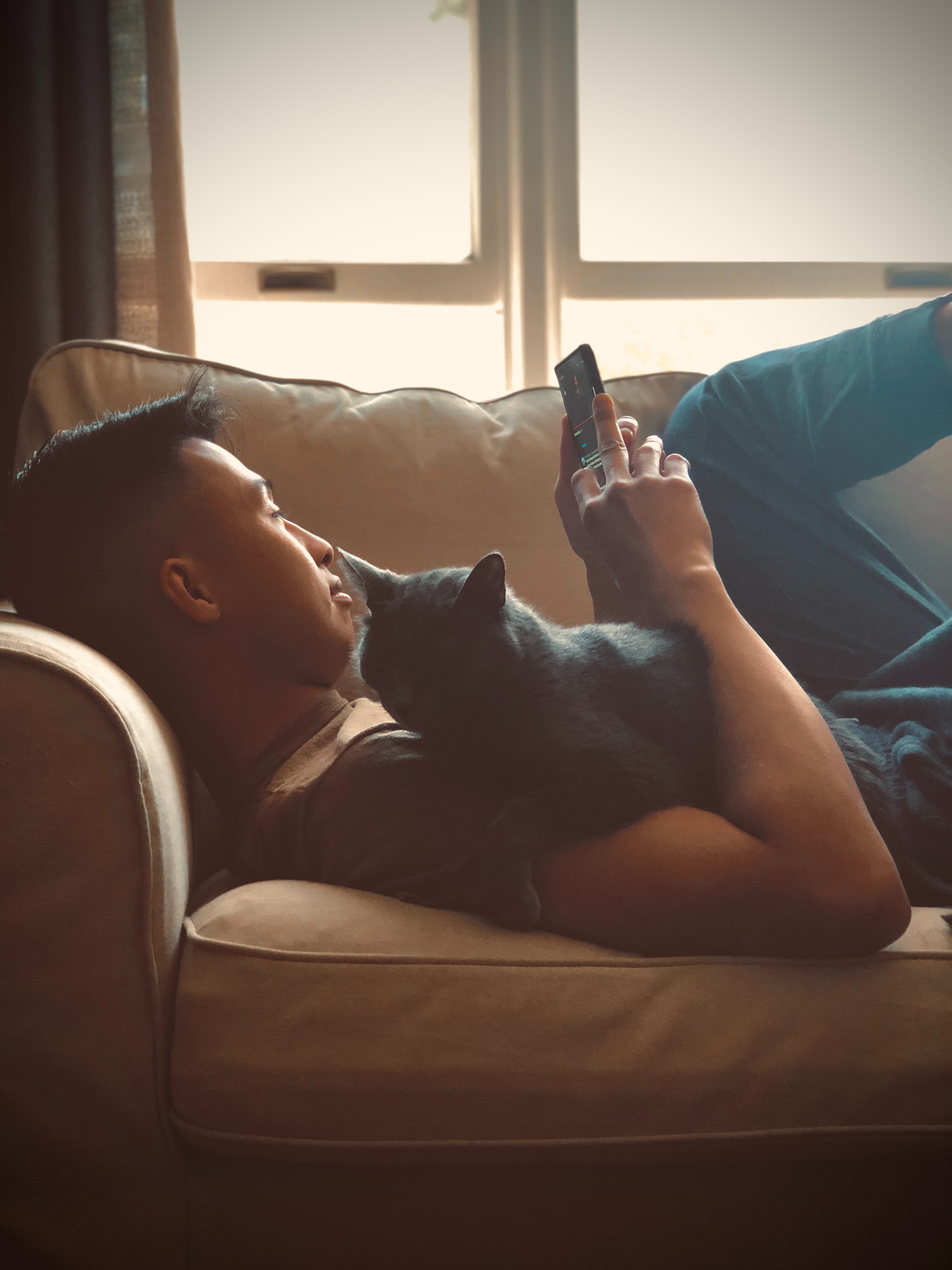 Man on couch with cat on lap surfing WEGO Health on phone