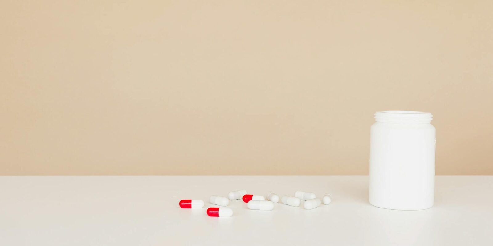 plastic jar with pile of capsules on table