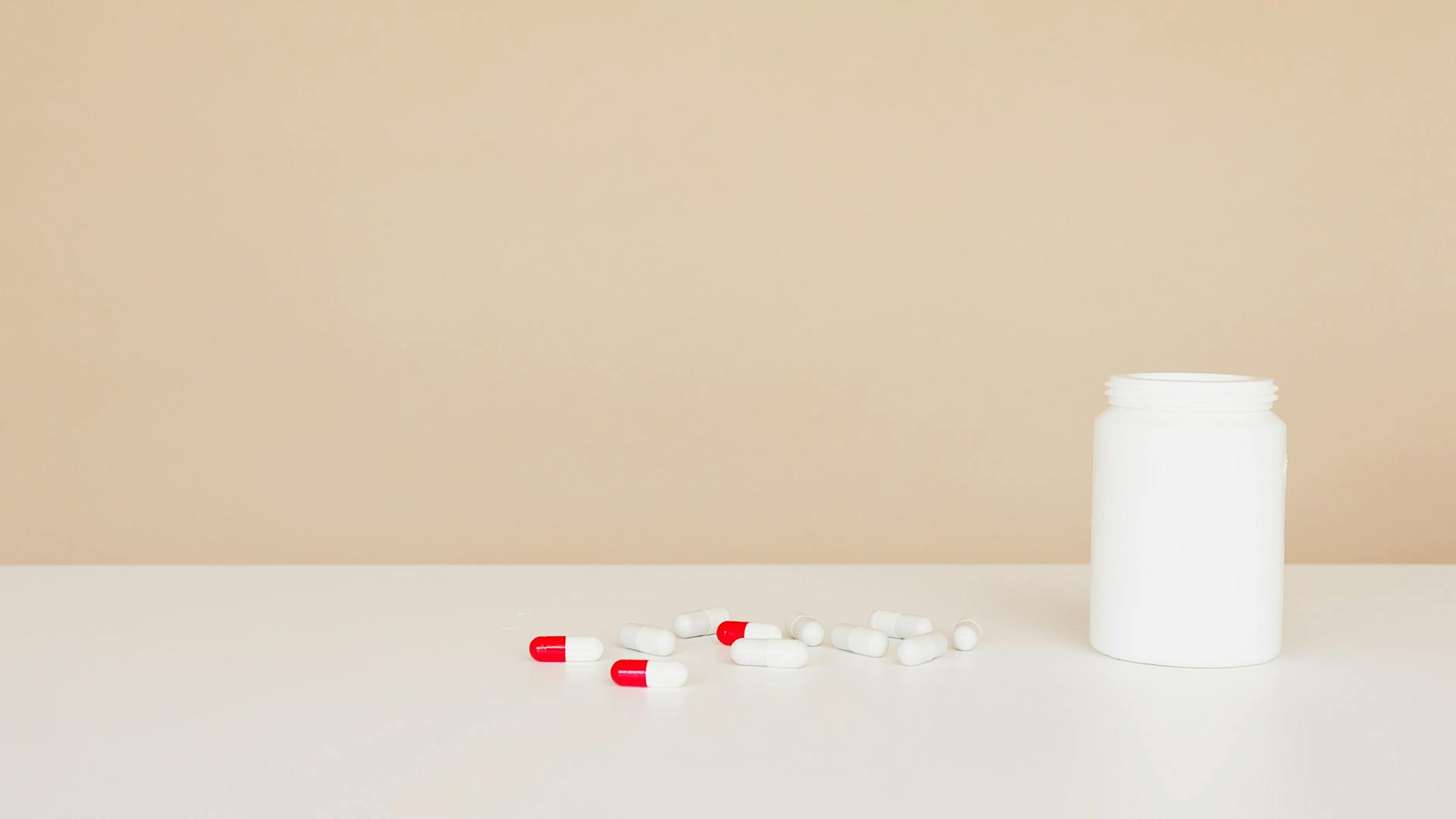 plastic jar with pile of capsules on table