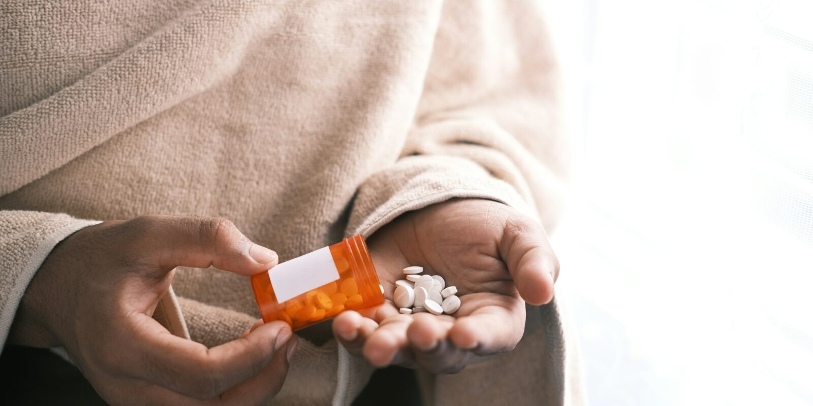 Woman holding bottle of pills in hand